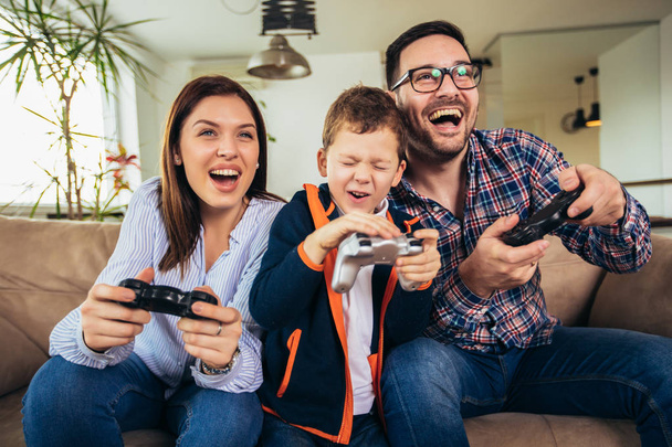 Щаслива сім'я сидить на дивані і грає у відеоігри та етикетку
 - Фото, зображення