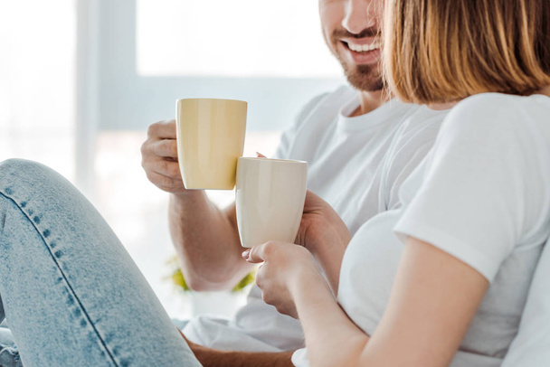 Cropped view of couple drinking coffee at home - Foto, imagen