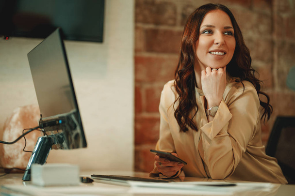 молодая успешная улыбающаяся женщина анализирует новый проект на компьютере в офисе
 - Фото, изображение