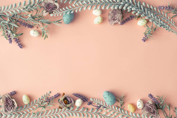 Creative layout made with spring flowers and leaves with Easter eggs on pastel pink background. Minimal natural composition  - Photo, Image