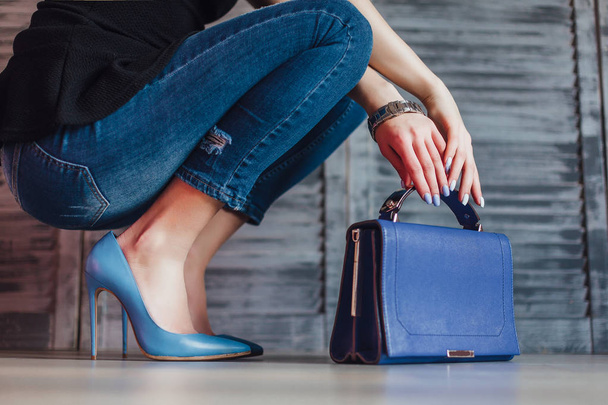 female hands holding bag, wearing in casual jeans and blue heels - Фото, зображення