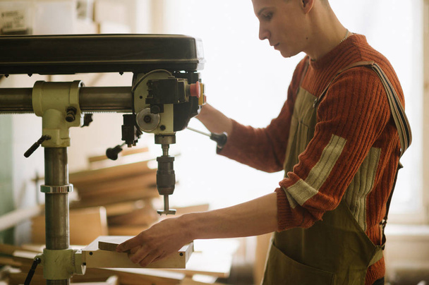 The master works on the machine for drilling in the carpentry workshop - 写真・画像
