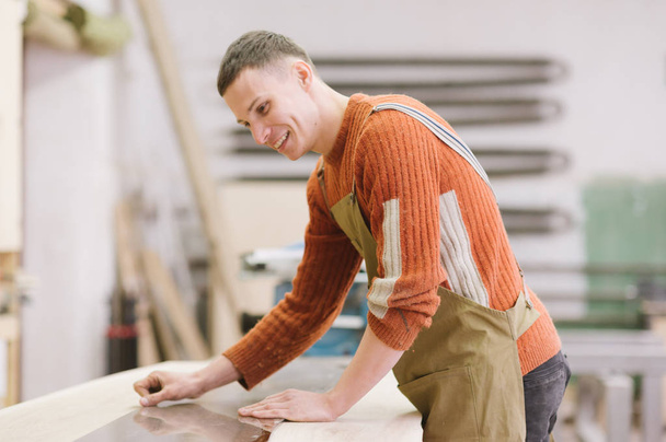 El maestro trabaja en una rectificadora de superficies en el taller de carpintería
 - Foto, imagen