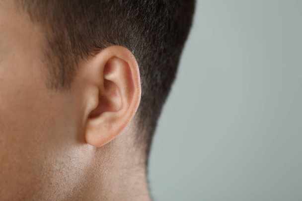 Young man with hearing problem on grey background, closeup - Photo, Image