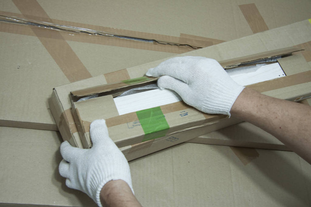 Male hands in white gloves with a knife unpack the box. - Foto, imagen