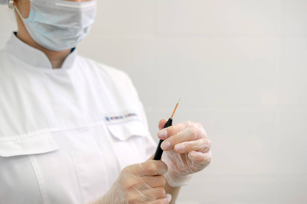 Dermatologa chirurgo femminile che prepara un electrocautery professionale per rimuovere talpa. Elettrocoagulazione a onde radio rimuovere metodo
 - Foto, immagini