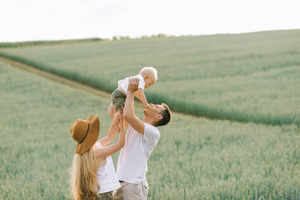 Молода сім'я розважається зі своєю маленькою дитиною в полі
 - Фото, зображення