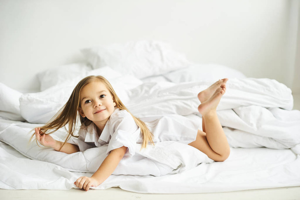 A portrait of beautiful little girl in the morning bedroom - Fotó, kép