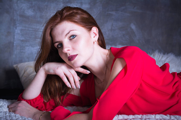 beautiful and sexy woman with red hair and dressed in a red dress - Photo, image