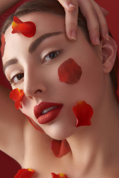 Face of thoughtful woman with petals of roses on her skin - Photo, Image
