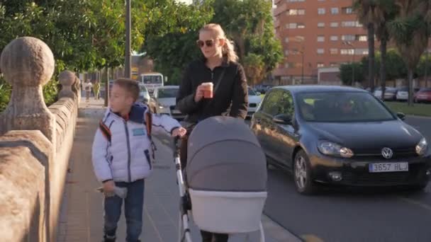 Woman with two kids walking in the city and drinking coffee - Filmagem, Vídeo