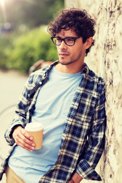 man in eyeglasses drinking coffee over street wall - Fotó, kép