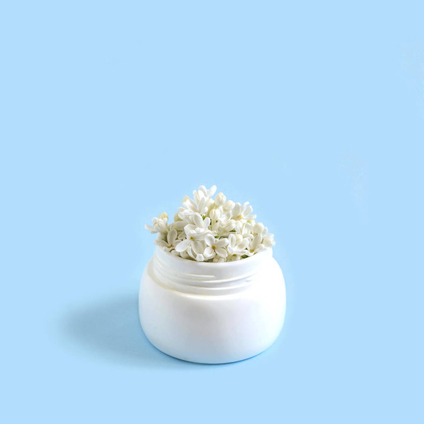 Jar with flowers of white lilac as cosmetic cream  - Photo, Image