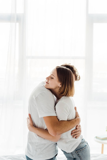 romantic couple in white t-shirts embracing at home - Fotoğraf, Görsel