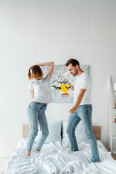 Full length view of couple in jeans dancing on bed - 写真・画像