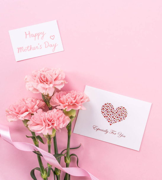 Beautiful fresh blooming baby pink color tender carnations isolated on bright pink background, mothers day thanks design concept,top view,flat lay,copy space,close up,mock up - Foto, immagini