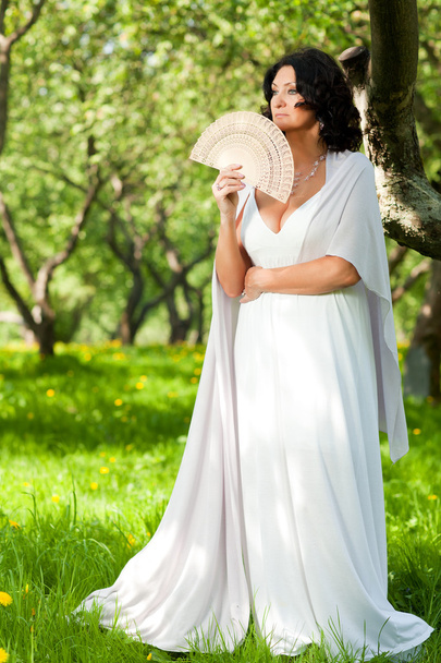 A woman in the park holds a fan - Φωτογραφία, εικόνα