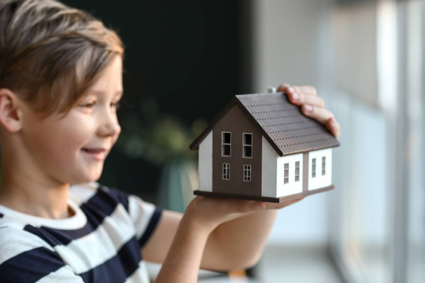 Little boy with model of house indoors. Concept of earthquake - Foto, imagen