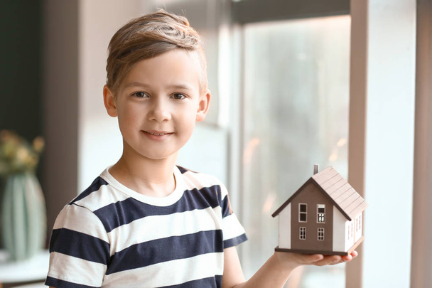 Маленький хлопчик з моделлю будинку в приміщенні. Концепція землетрусу
 - Фото, зображення
