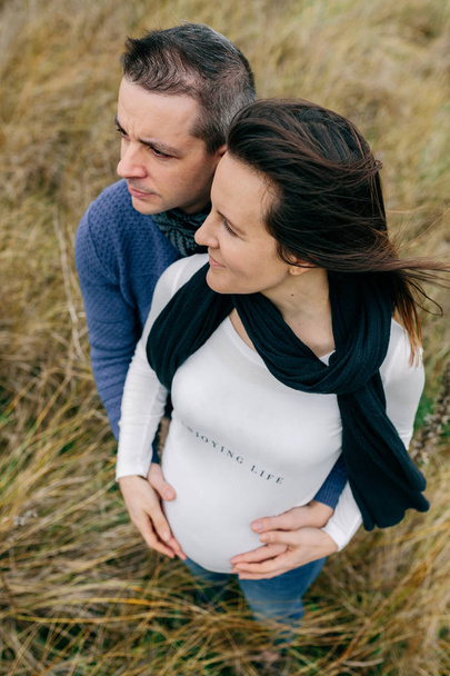 Embarazada con pareja abrazando y sosteniendo el vientre
 - Foto, imagen