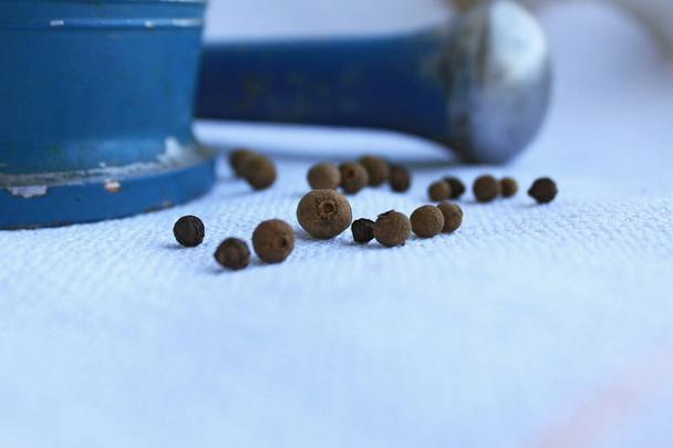 Maíz de pimienta negra en mortero metálico antiguo con mortero sobre fondo de lino
 - Foto, imagen