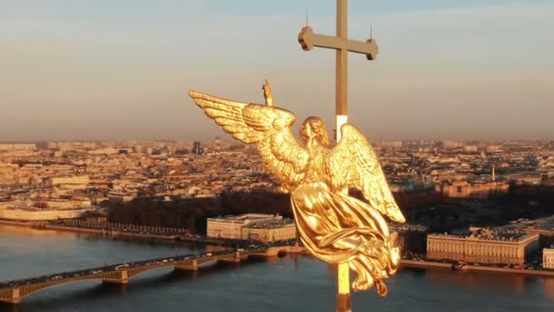Vliegen rond een engel op de torenspits van Peter en Paul Fortress bij zonsondergang, close-up. Panorama van historisch centrum van St. Petersburg - Video