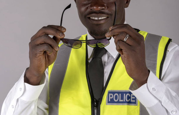  Портрет усміхненого поліцейського у формі і тримає пару темних окулярів. Квітень 2019
 - Фото, зображення