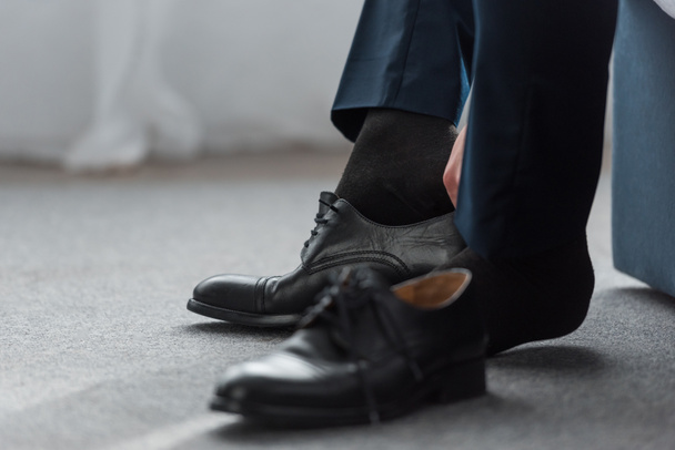 cropped view of man wearing black shoe at home  - Photo, Image