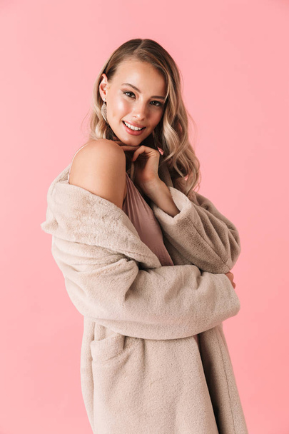 Pretty woman posing isolated over pink wall background dressed in fashion coat. - Photo, image