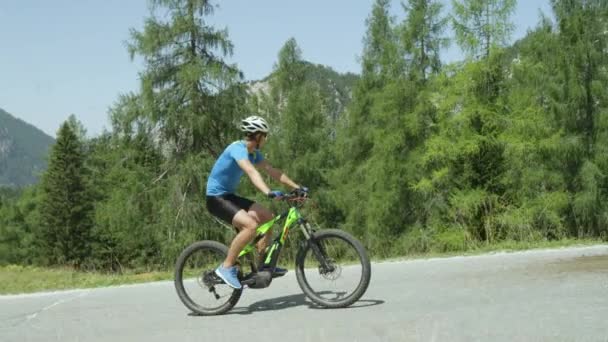 Atletische jonge mannelijke intensivering op pedalen van zijn koele weg fiets tijdens de intense berg race. Pro wielrenner training in de zonnige bergen. Pittoreske fietstocht in de zomer natuur. Slow motion beelden - Video