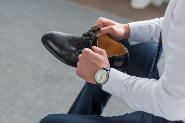 vista recortada del hombre sosteniendo zapato negro en las manos
  - Foto, Imagen