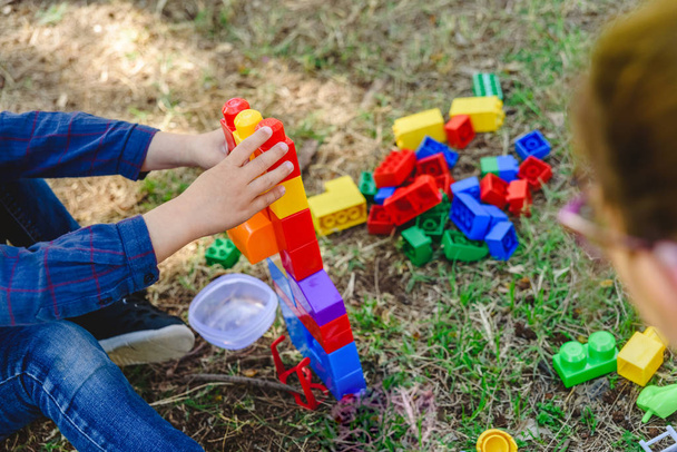Child playing with colorful blocks sitting on the ground of a ga - Photo, Image
