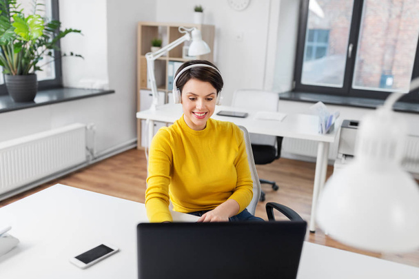 businesswoman with headphones and laptop at office - Fotó, kép