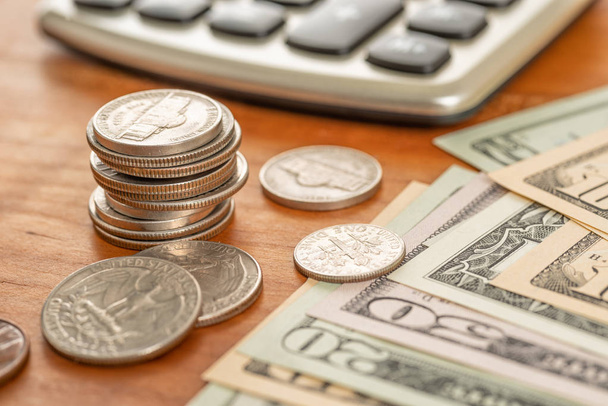 Montón de monedas con billetes de dólar y una calculadora
 - Foto, imagen