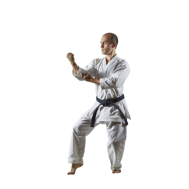 Yetişkin atlet beyaz izole arka planda resmi karate egzersizleri gerçekleştirir - Fotoğraf, Görsel