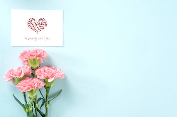 Beautiful fresh blooming baby pink color tender carnations isolated on bright blue background, mothers day thanks design concept,top view,flat lay,copy space,close up,mock up - Foto, imagen