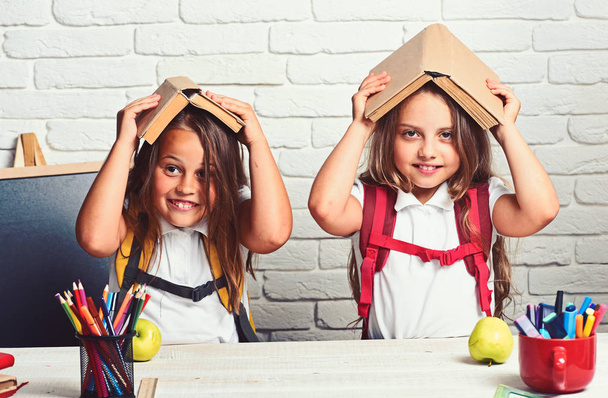 Cheerful smiling little girls with books on head. Looking at camera. School concept. Back to School. - Φωτογραφία, εικόνα