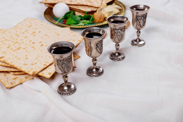 Passover matzoh jewish holiday bread, four glasses kosher wine over wooden table. - Photo, Image