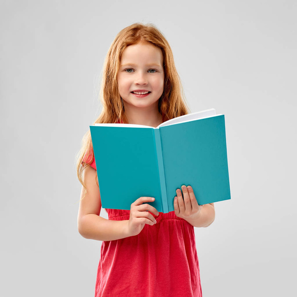 smiling red haired girl reading book - Fotoğraf, Görsel