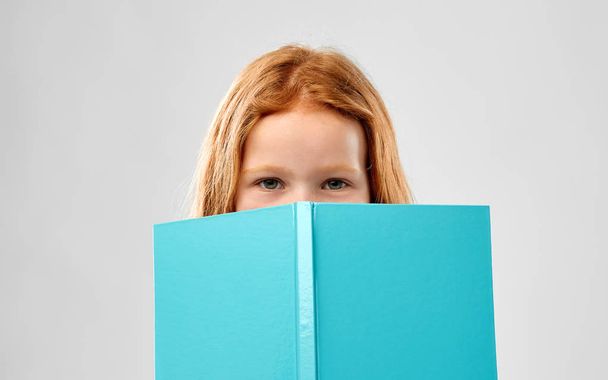 smiling red haired girl reading book - Valokuva, kuva