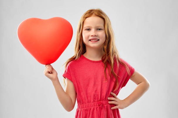 smiling red haired girl with heart shaped balloon - Фото, изображение