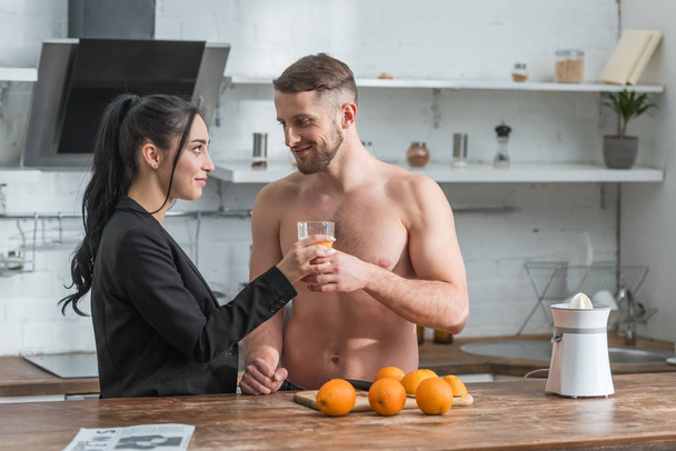 魅力的な女の子に新鮮なオレンジジュースのグラスを与えるひげの筋肉の男  - 写真・画像