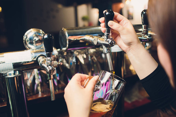 Mans hand pouring pint of beer behind the bar. - Photo, Image
