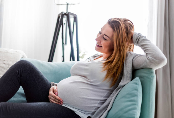 Pregnant woman relaxing at home on the couch - Foto, Imagem
