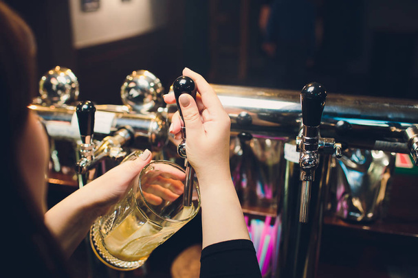 Mans hand pouring pint of beer behind the bar. - Valokuva, kuva