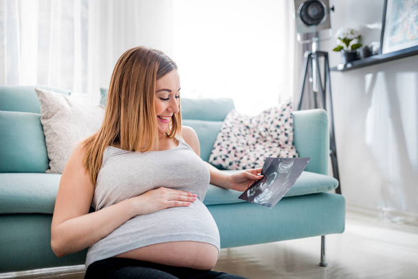 Pregnant woman looking her baby on ultrasound image, usg photo - Fotó, kép