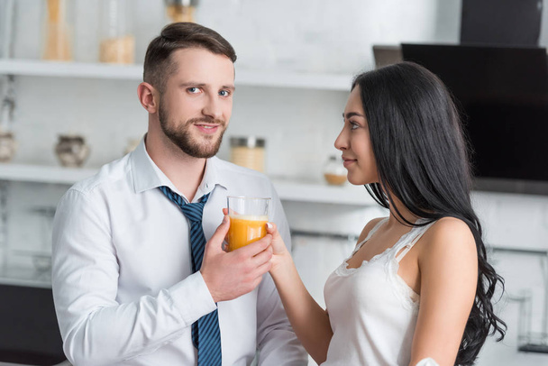 Ελκυστική μελαχρινή κορίτσι δίνοντας νόστιμο χυμό πορτοκάλι σε όμορφο άντρα  - Φωτογραφία, εικόνα