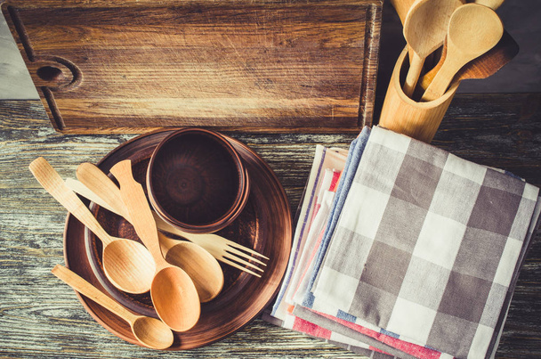 Chapas de cerâmica, talheres de madeira ou de bambu, tábua de corte vintage e toalhas no interior da cozinha
. - Foto, Imagem