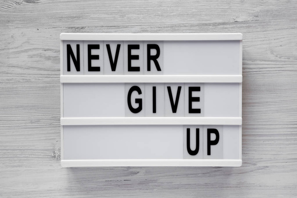 'Never give up' words on lightbox over white wooden background.  - Foto, Imagem