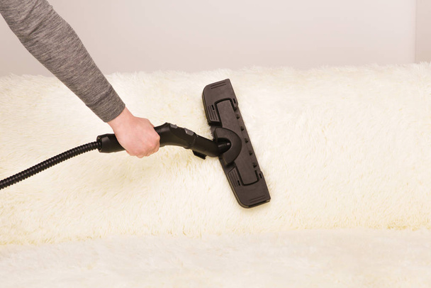 Jeune femme avec un nettoyeur à vapeur nettoie le tapis sur le canapé
 - Photo, image